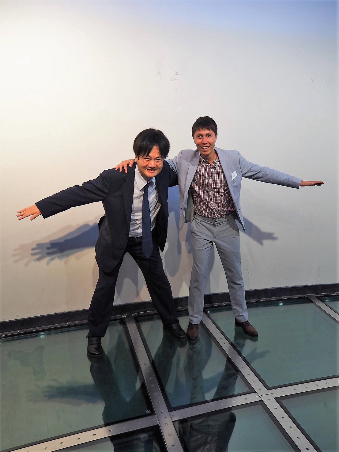 △トロントのＣＮタワー展望台にあるガラスの床の上に立つ大塚圭一郎（左）。右はトロントグローバル勤務のショーン・ムイタマーズさん